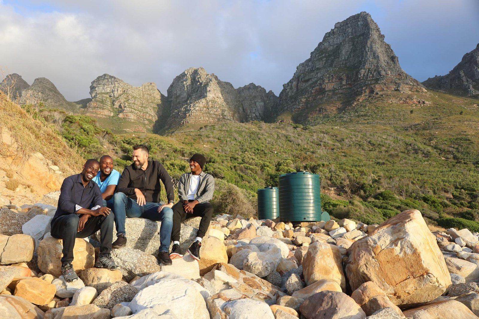 The Makulu team on the rocks with green tanks and mountains behind